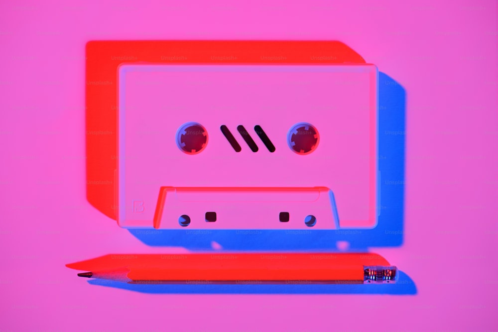 toned pink picture of retro audio cassette and pencil on tabletop