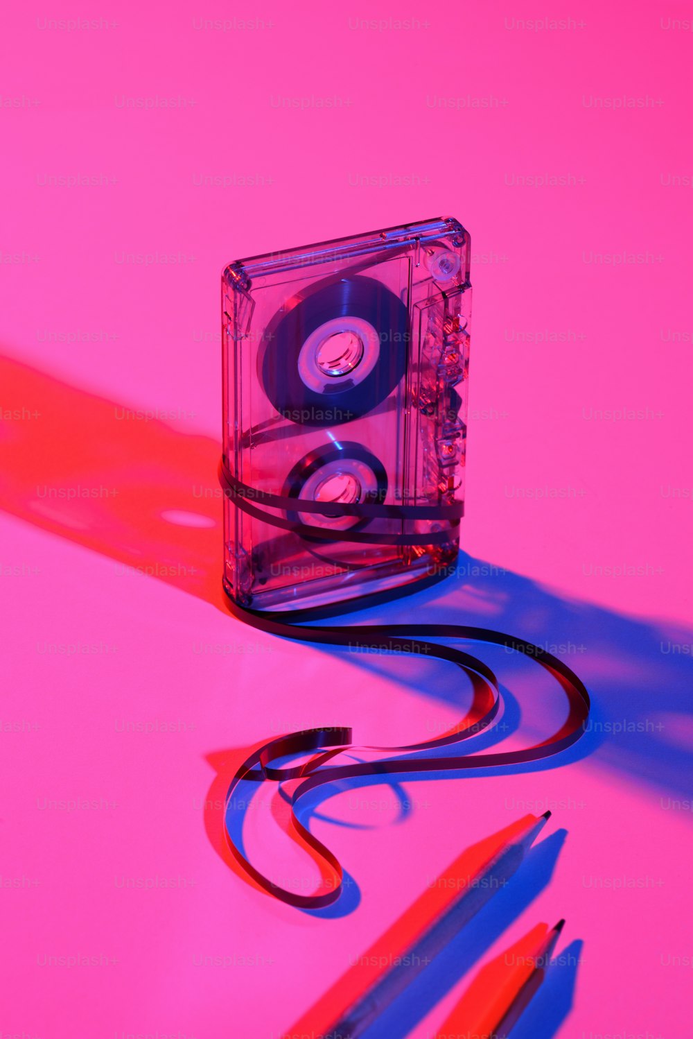 close up view of retro audio cassette and pencils on pink backdrop