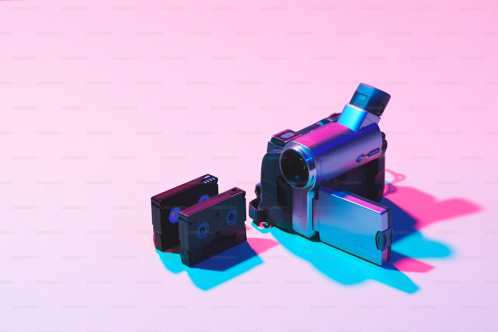 ピンクの背景に配置されたビデオカセットとデジタルビデオカメラの接写