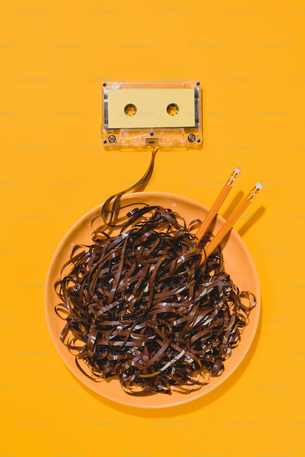 Flache Verlegung mit Retro-Audiokassette und Schüssel mit Bleistiften und Klebeband isoliert auf gelb