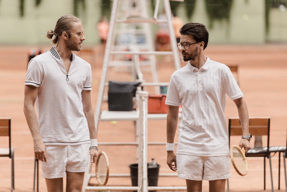 retro styled tennis players walking and looking at each other before game at tennis court
