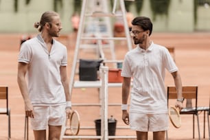 Jugadores de tenis de estilo retro caminando y mirándose antes del partido en la cancha de tenis