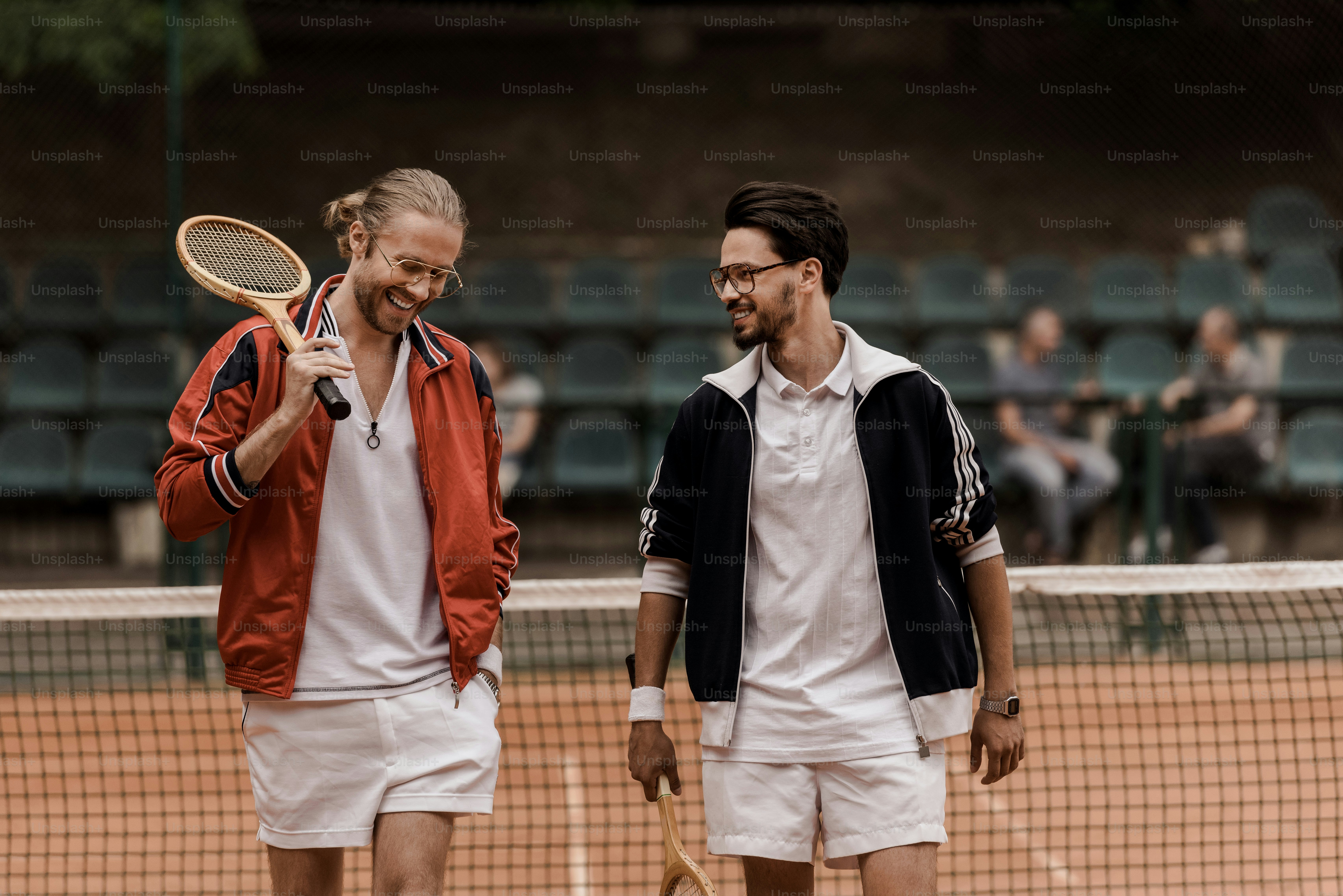 Sorridenti giocatori di tennis in stile retrò che camminano con le racchette al campo da tennis