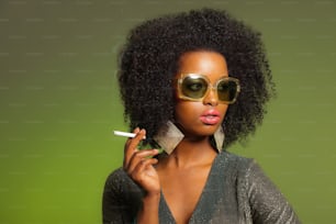 Fumar retrô 70s moda afro mulher com vestido verde e óculos de sol. Fundo verde.