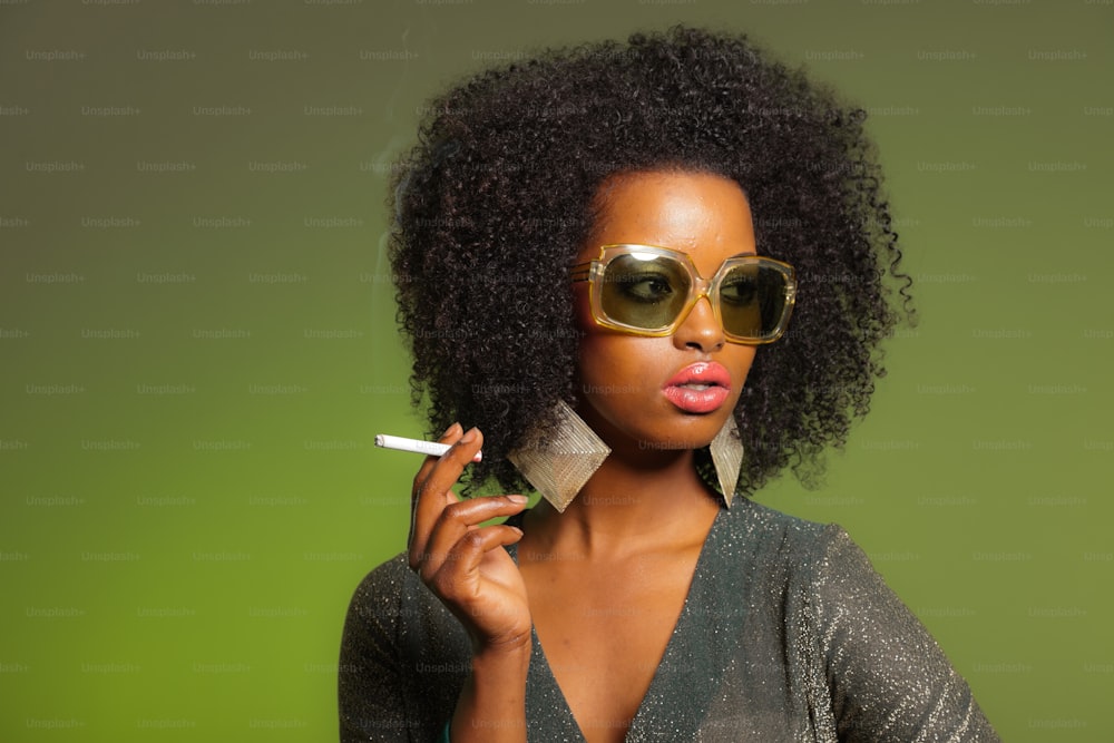 Smoking retro 70s fashion afro woman with green dress and sunglasses. Green background.
