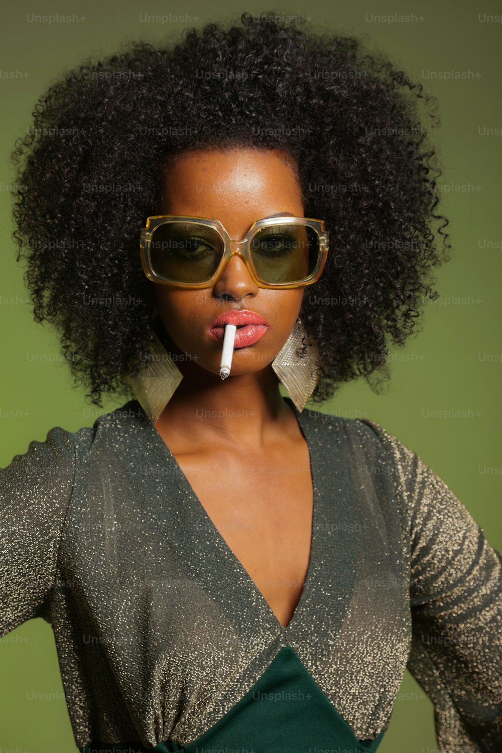 Smoking retro 70s fashion afro woman with green dress and sunglasses. Green background.