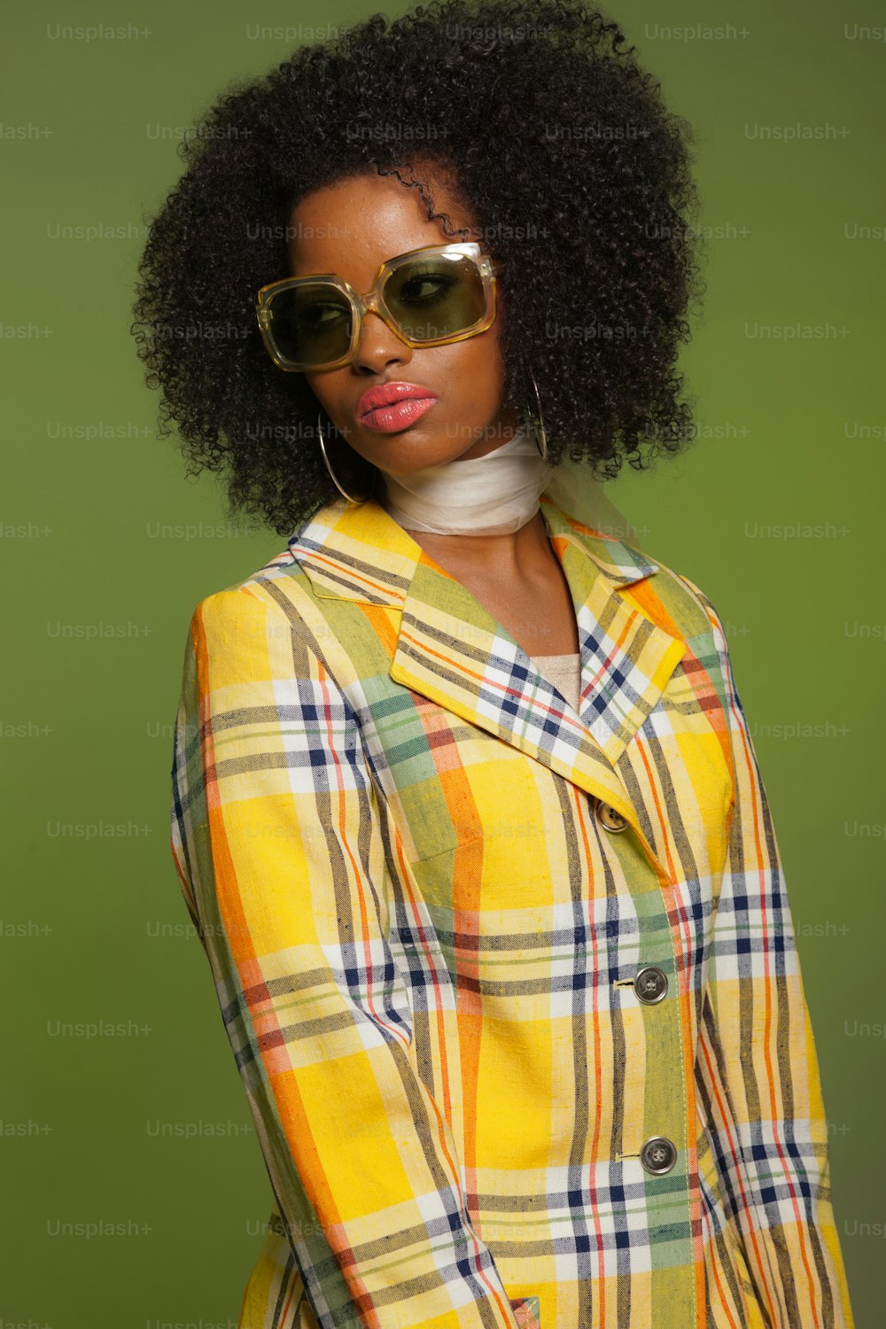 Retro 70s fashion style african woman with sunglasses. Yellow jacket and green background.