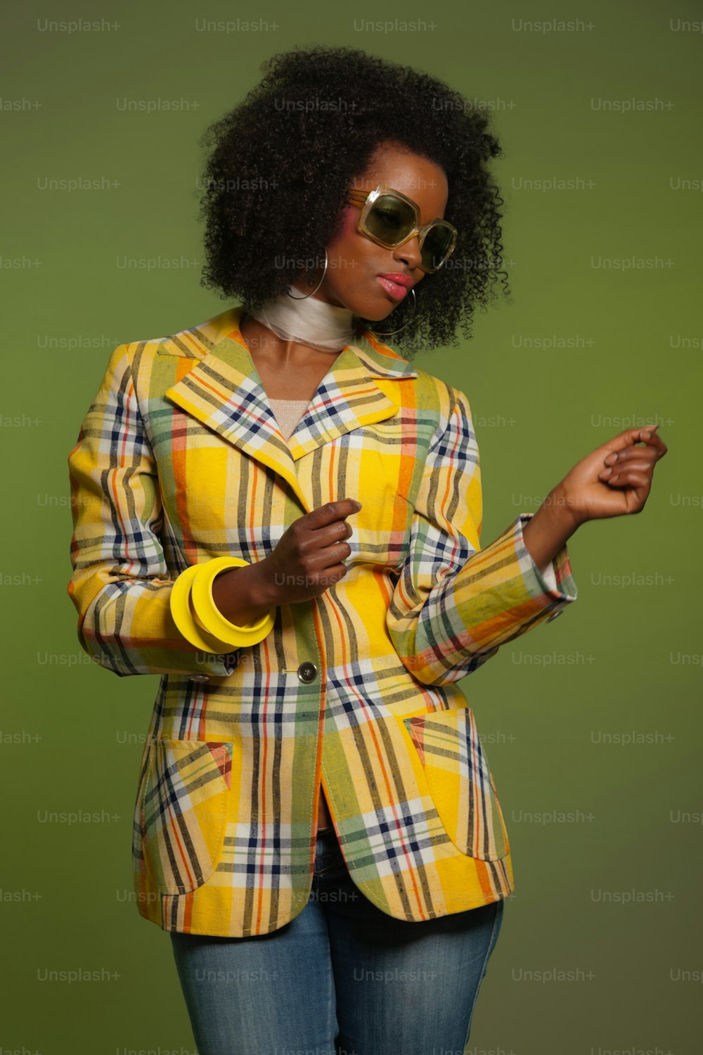 Dancing retro 70s fashion african woman with sunglasses. Yellow jacket and green background.
