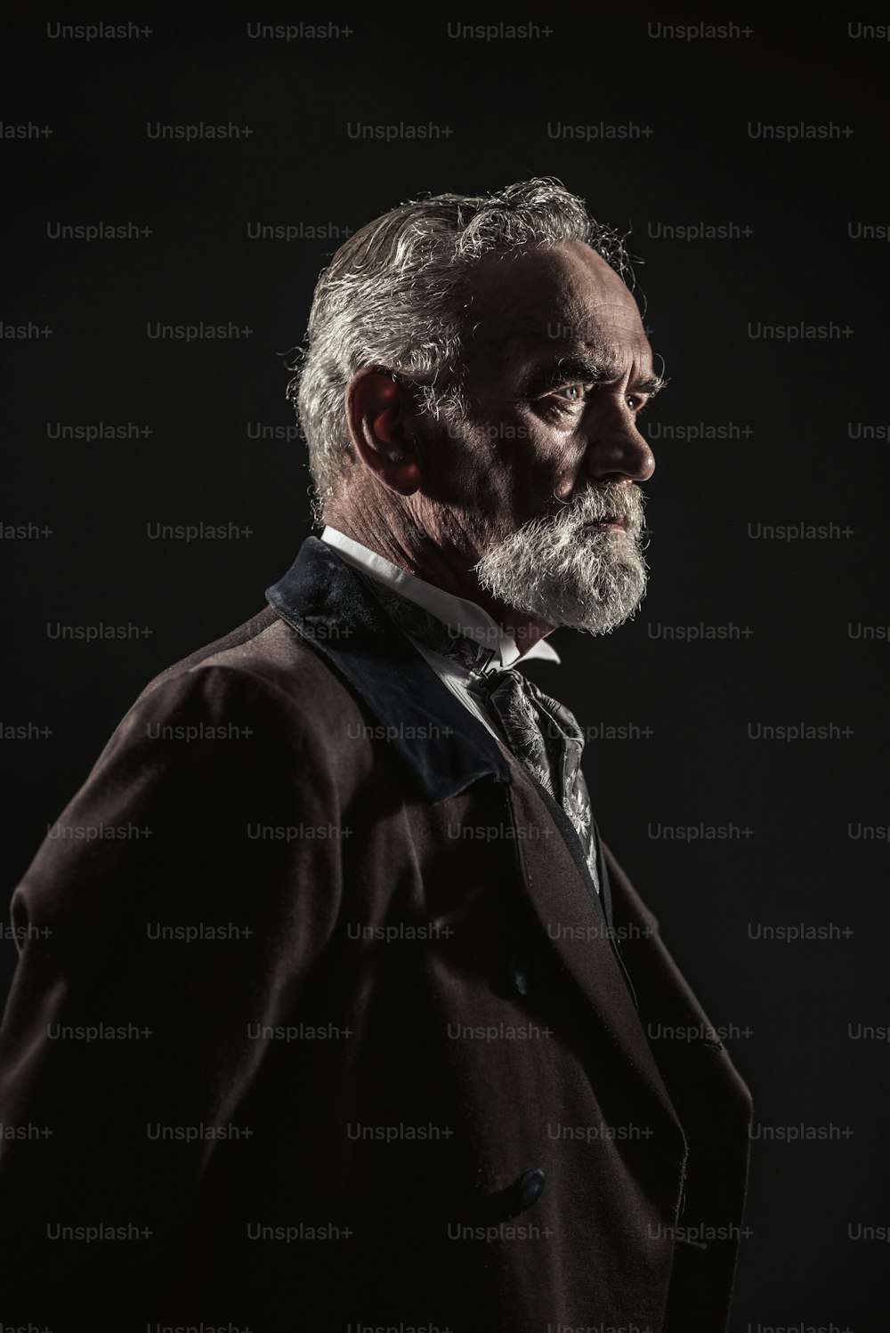 Vintage characteristic senior man with gray hair and beard. Studio shot against dark background.