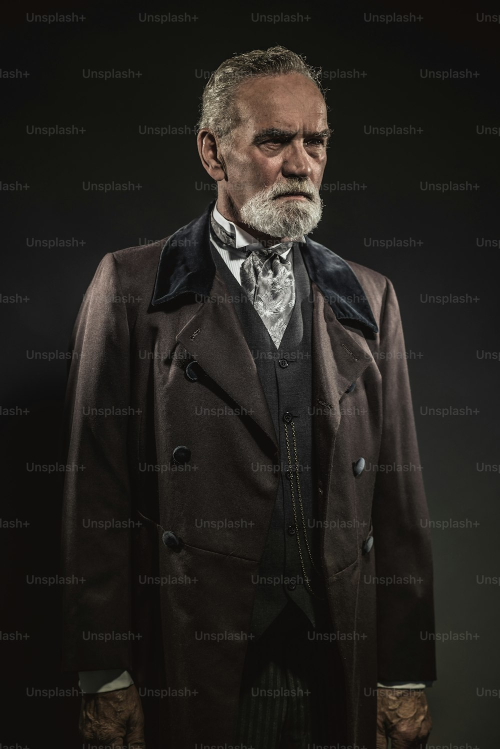 Vintage caractéristique homme senior avec des cheveux gris et une barbe. Plan en studio sur fond sombre.