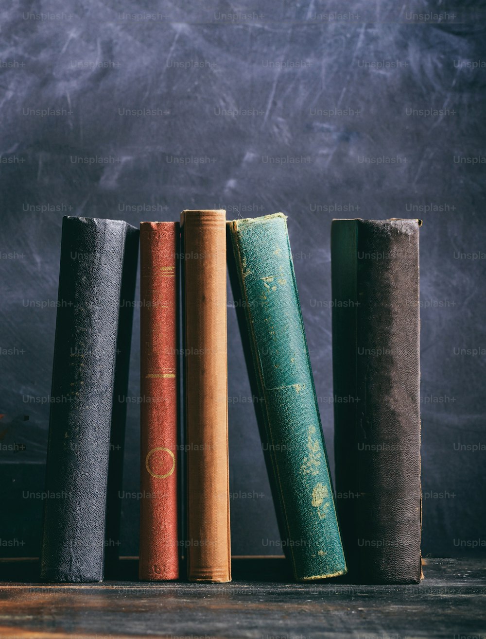 Old books on a wooden shelf, black board background. Law, history library shelf, vertical shot