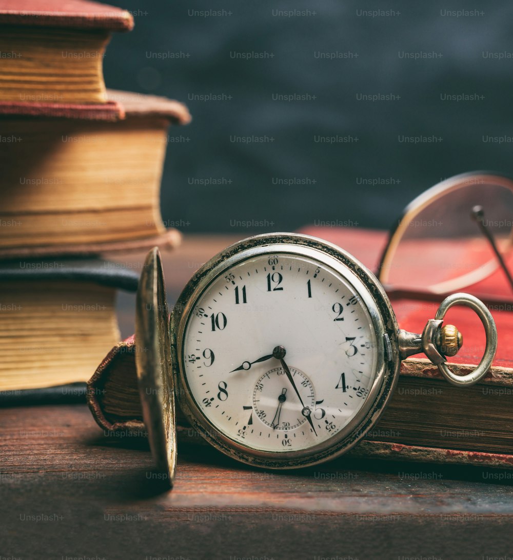 Relógio de bolso vintage e livros velhos em um fundo de mesa de escritório de madeira. Tempo, conceito de ciência