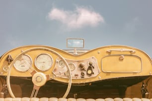 Driver view of a two seater vintage classic open cabriolet car in front of a sunny blue sky