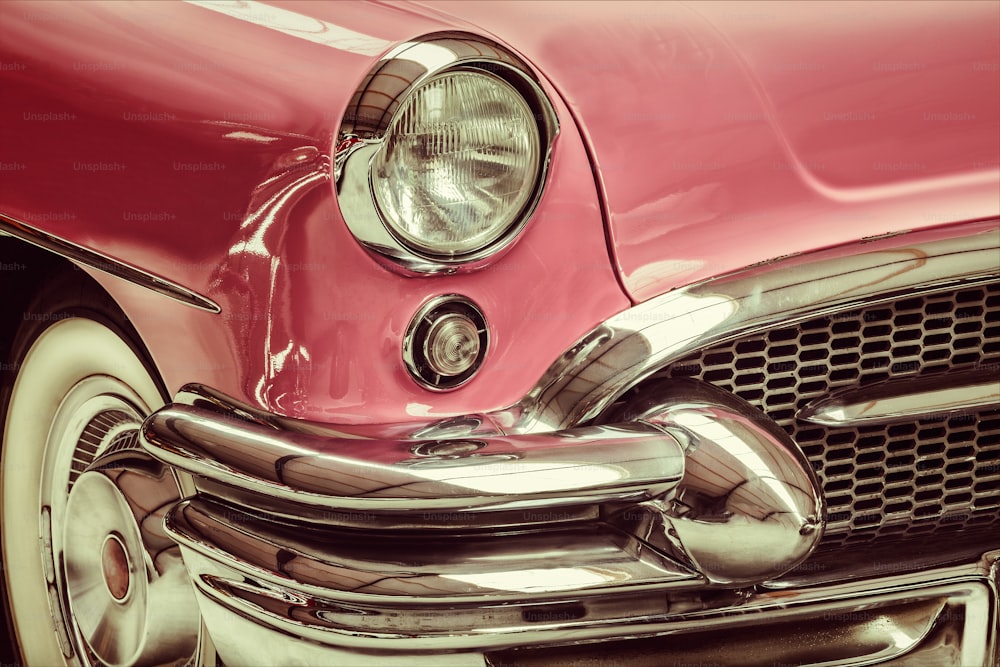 Retro styled image of a front of a pink classic car