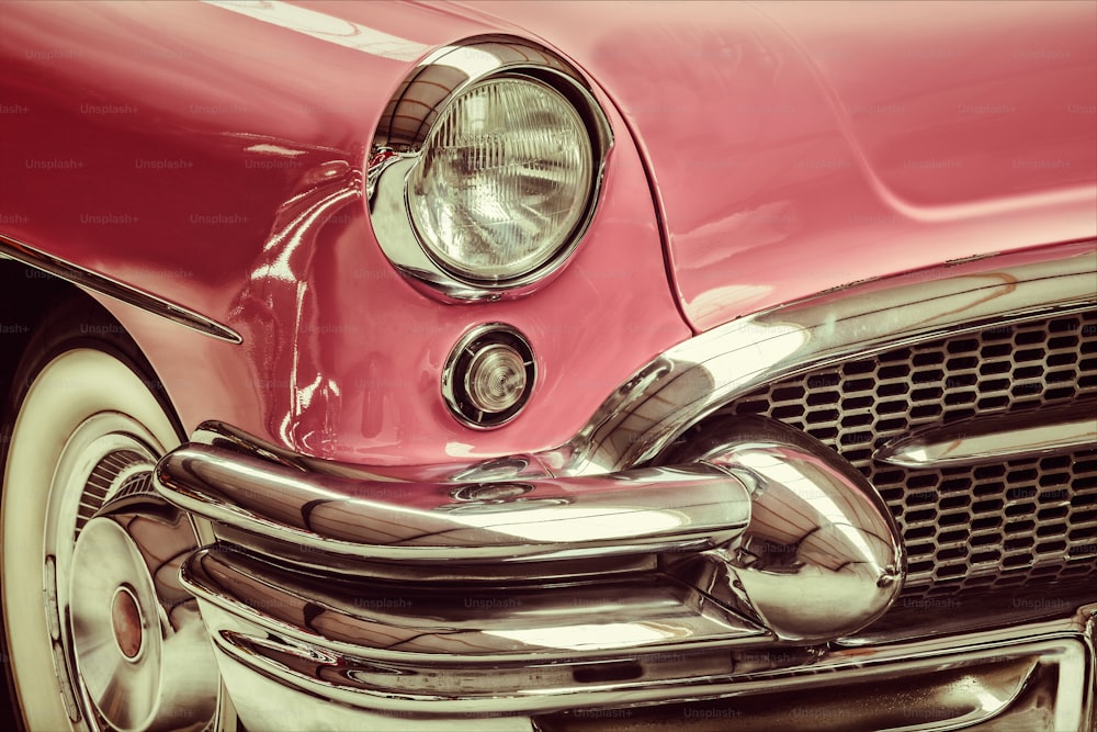 Retro styled image of a front of a pink classic car