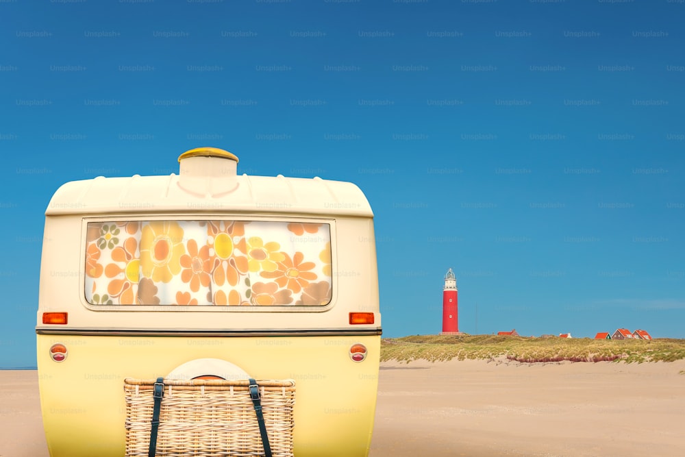 Vintage rear of a caravan in two tone yellow and white in front of a Dutch beach on the island of Texel