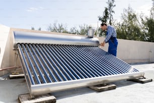 Idraulico maschio che ripara la caldaia elettrica dell'energia solare