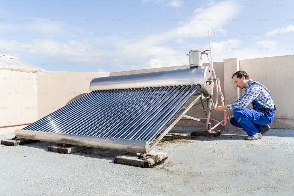 太陽エネルギー電気ボイラーを修理する男性の配管工