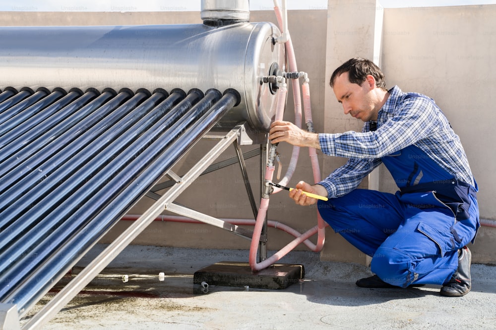Male Plumber Repairing Solar Energy Electric Boiler