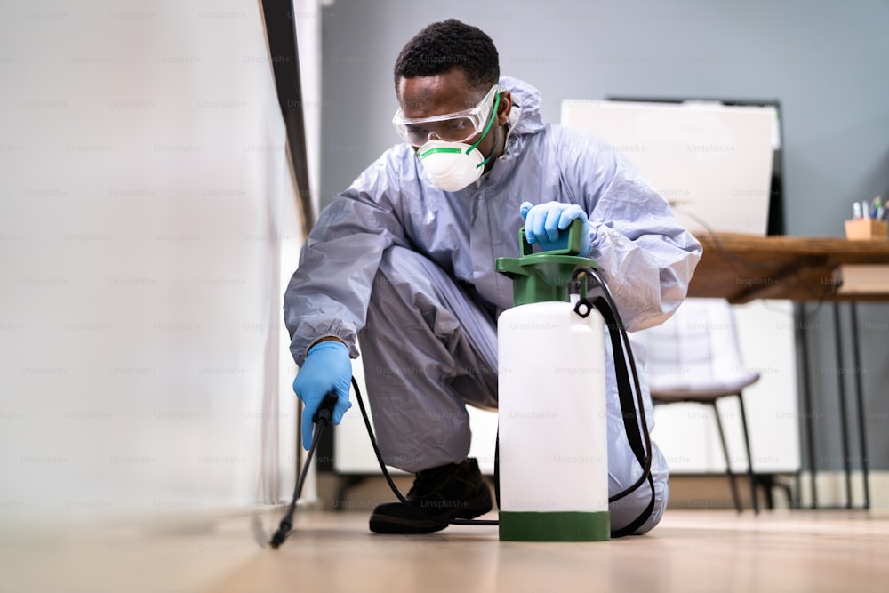 Control de plagas Exterminador Hombre rociando pesticidas termitas en la oficina