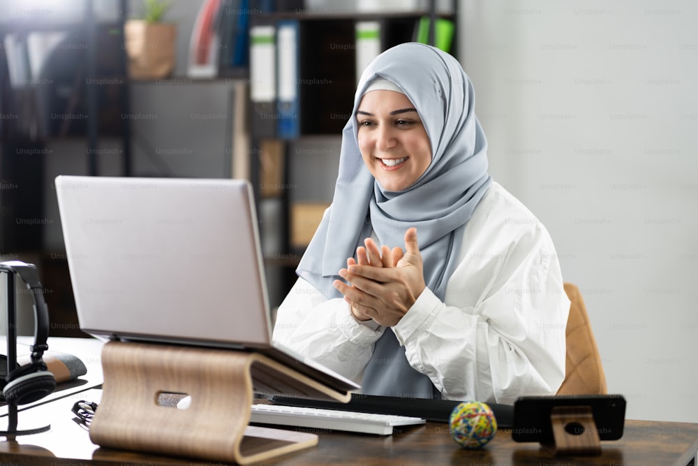 Mujer musulmana aplaude en una reunión virtual de videoconferencia en línea