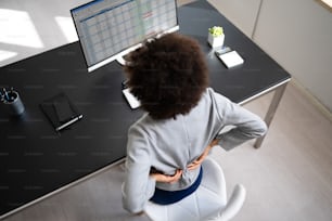 背中の痛み悪い姿勢の女性がオフィスに座っている