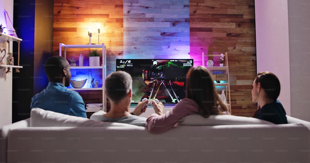 自宅でビデオゲームをプレイする人々の背面図