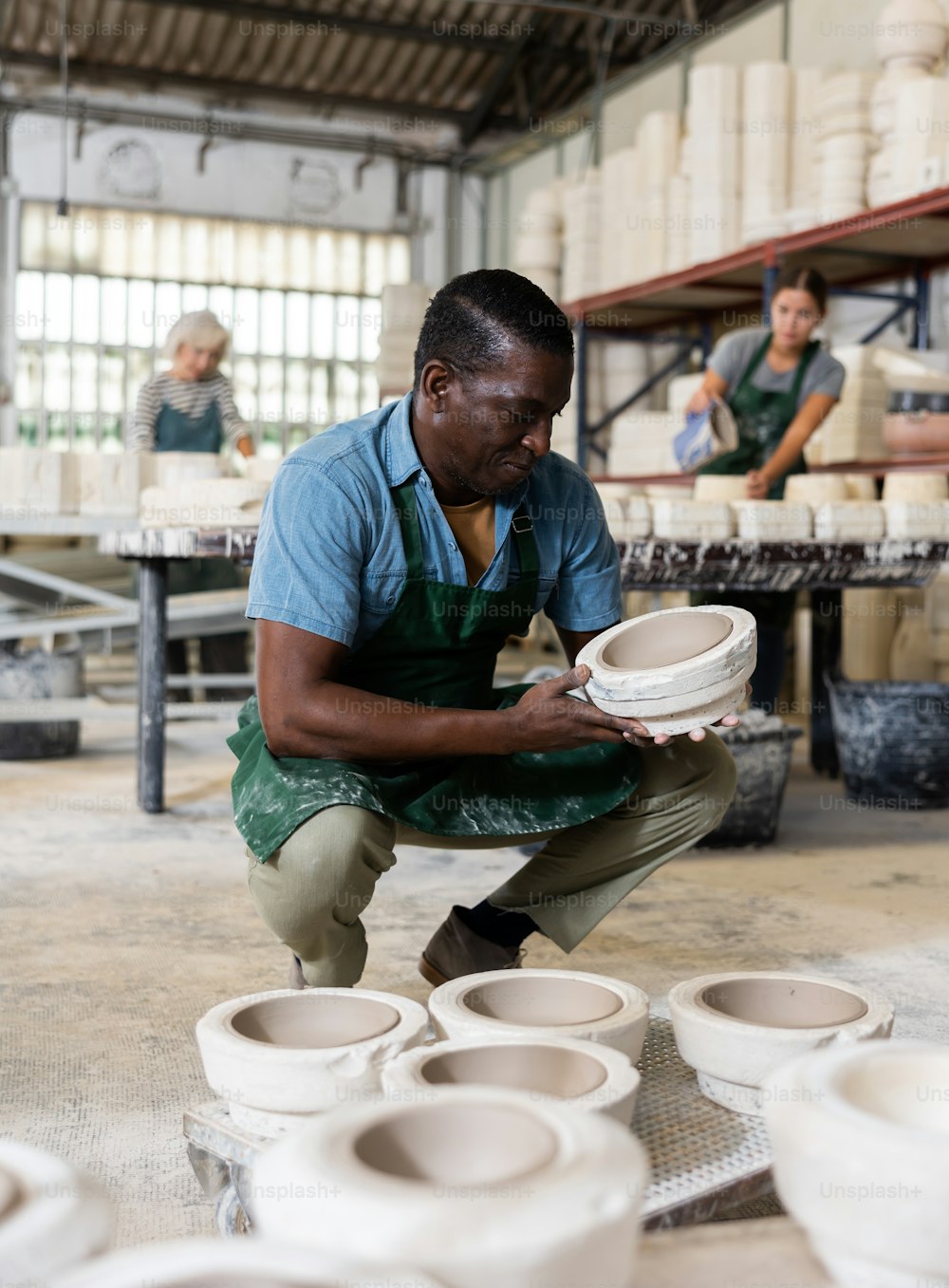 기쁜 아프리카계 미국인 노동자가 도자기 공장에서 도자기용 석고 틀의 절반을 시연합니다.