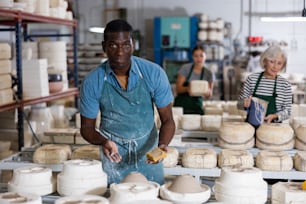 African american man prepares pottery with a foam sponge - removes roughness and unevenness