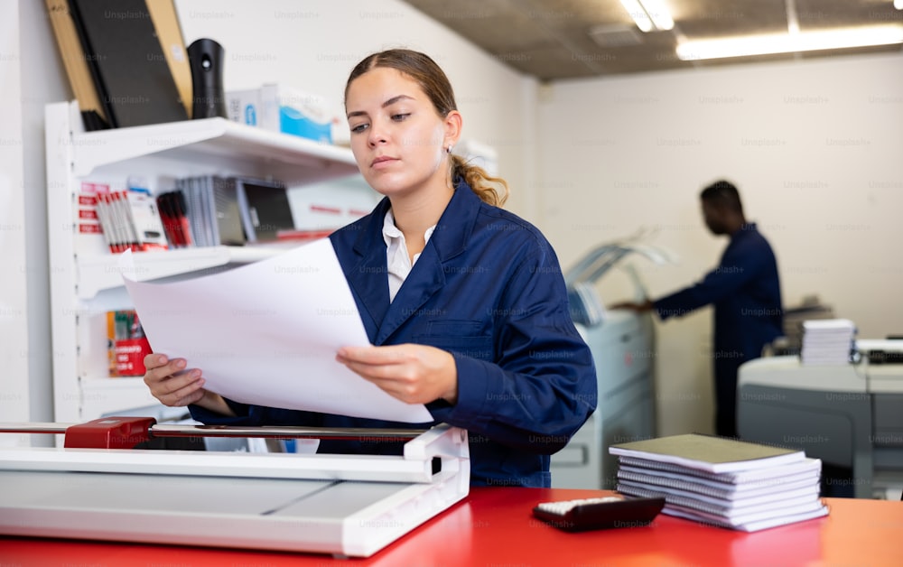 Portrait of an attentive woman checking quality of printing in a printing house