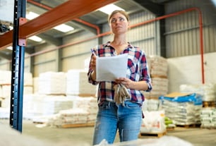 Portrait of caucasian woman working in warehouse, checking documentation.