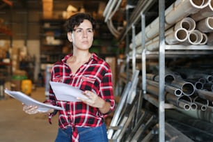 Positive female storekeeper checks presence of goods in the building materials warehouse