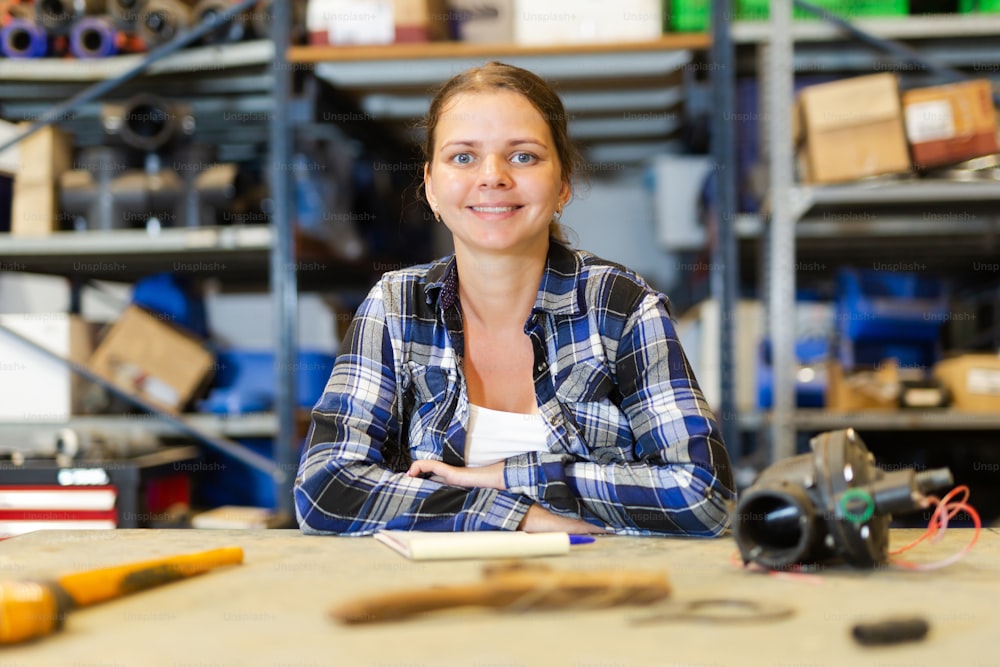 Satisfied female employee of hardware store posing in a warehouse