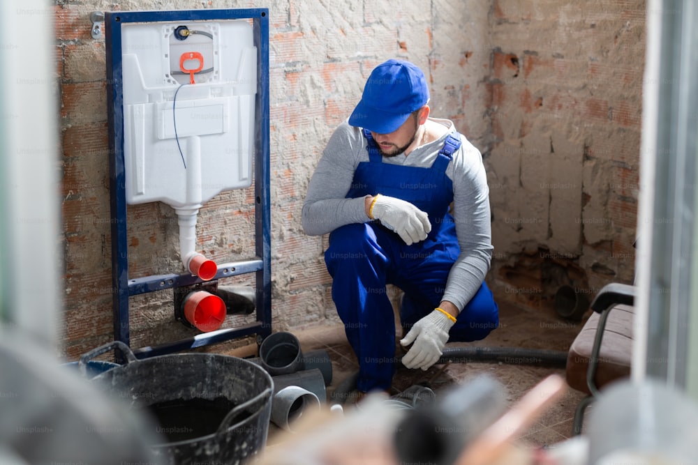 Portrait of plumber in blue overall next to a sewerage system being installed