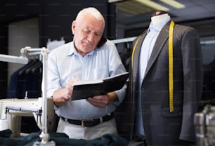 Professional tailor man talking on mobile phone and making notes in a notebook