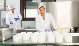 Femme portant un uniforme montrant le processus de production du fromage cottage dans une usine laitière