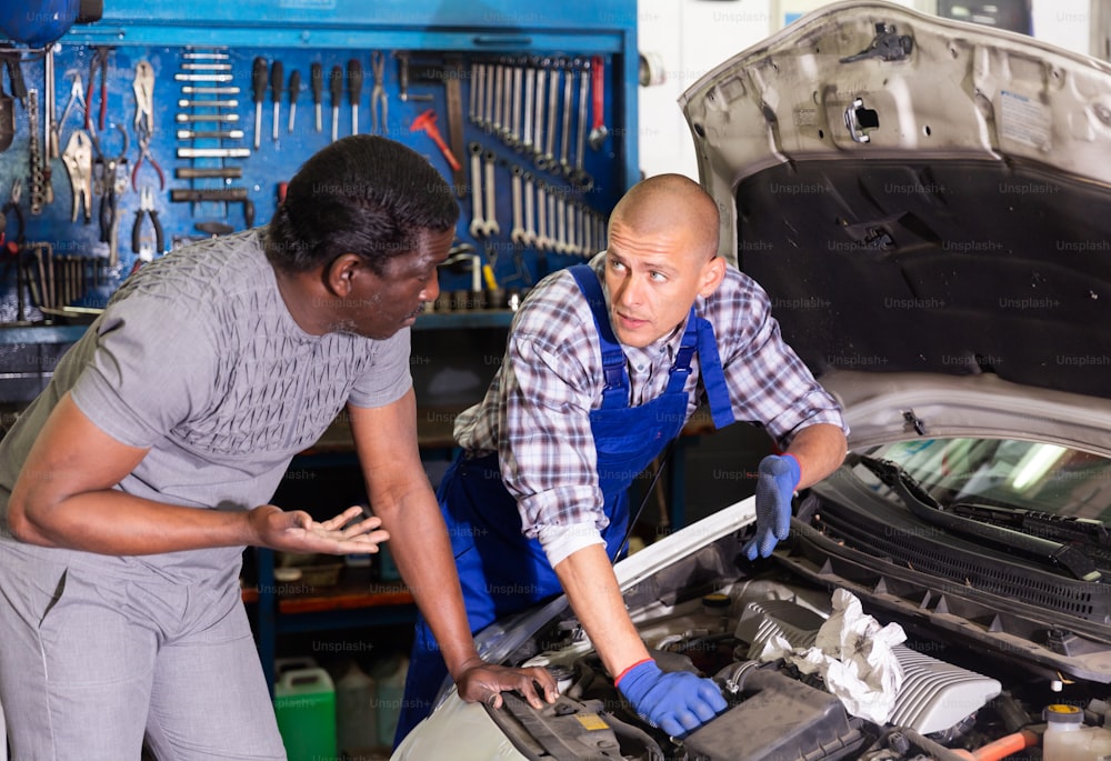 Two car mechanic diagnosing auto engine problem in auto service