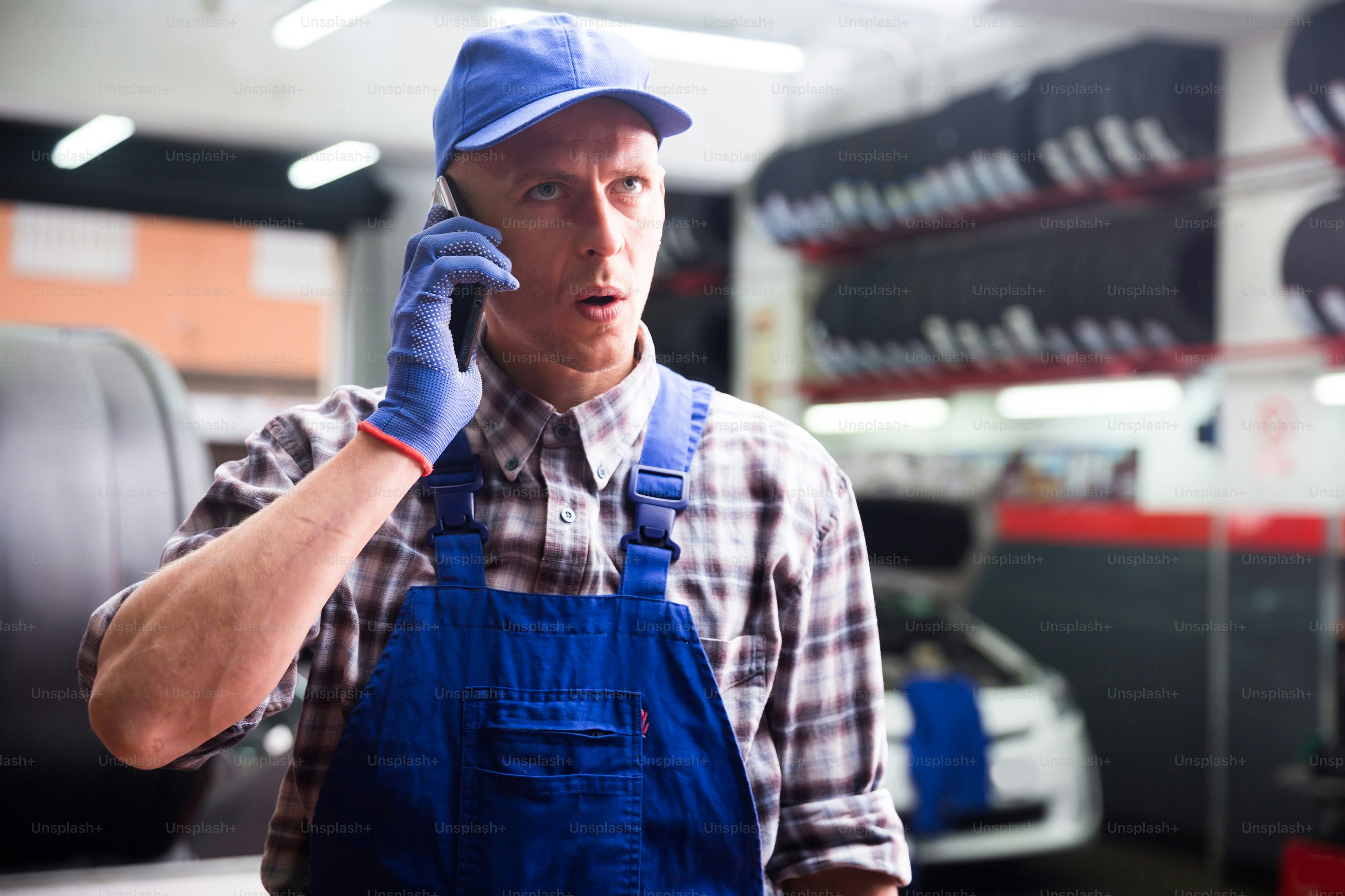 Confident auto mechanic talking on a smartphone in a car service