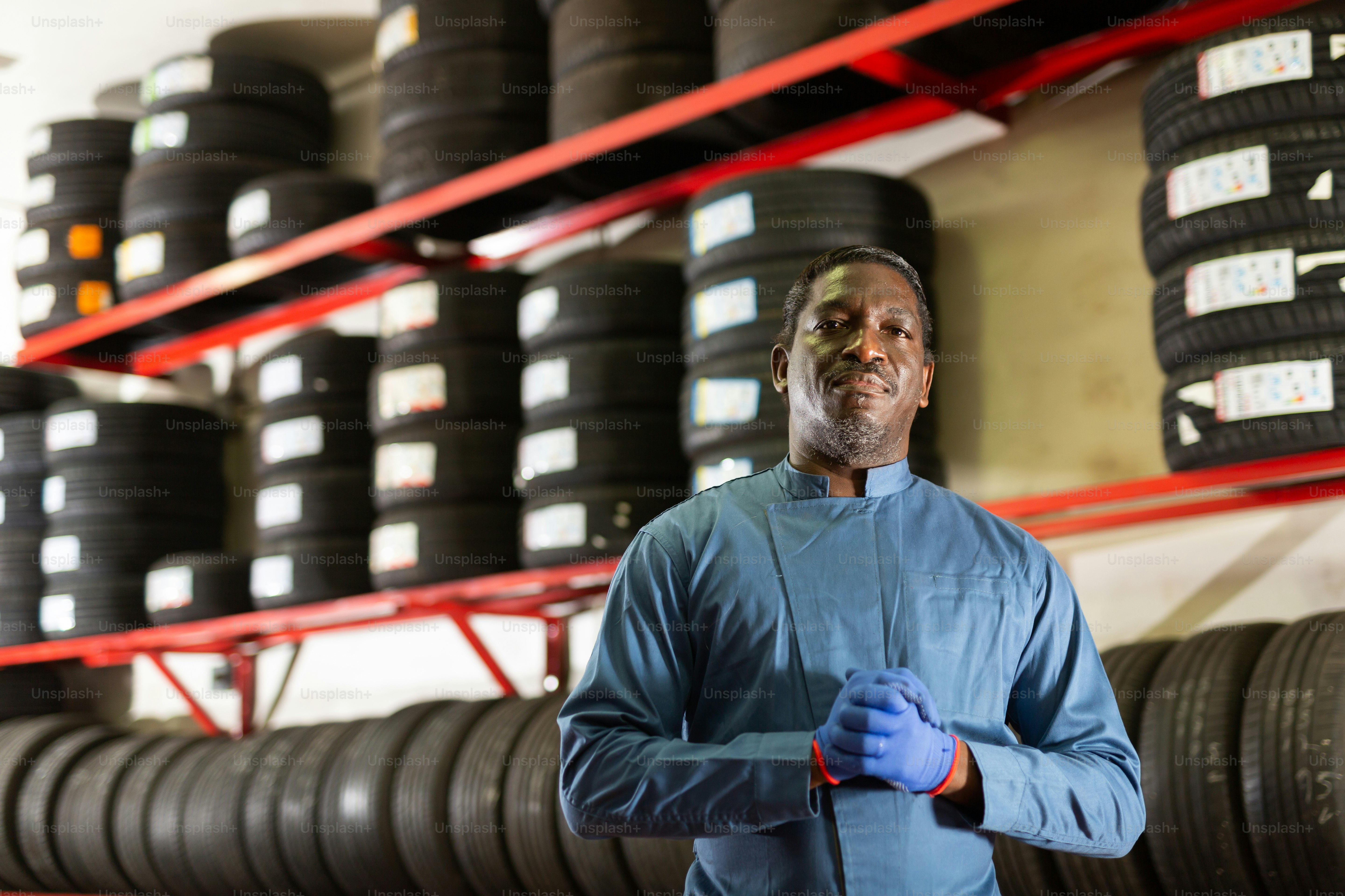 Portrait of a serious auto mechanic in front of car tires