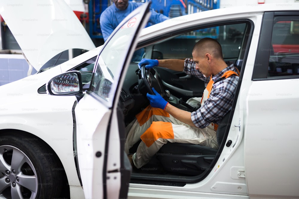 Serviceman making car diagnostics in workshop