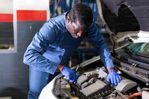 Professional man car mechanician repairing car in auto repair shop