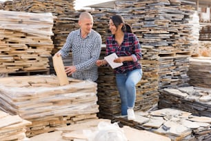 Couple of clients checkin quality of natural stone tiles at warehouse of building materials