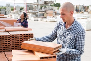 Trabajador apila paneles de aislamiento térmico en el almacén de materiales de construcción