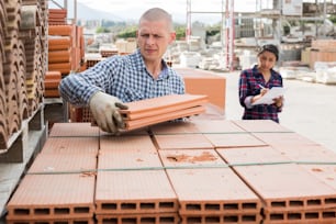 Young man working at hardware store warehouse, holding in hands insulation panel