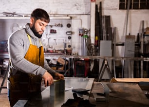 Foreman measures part and takes notes on paper