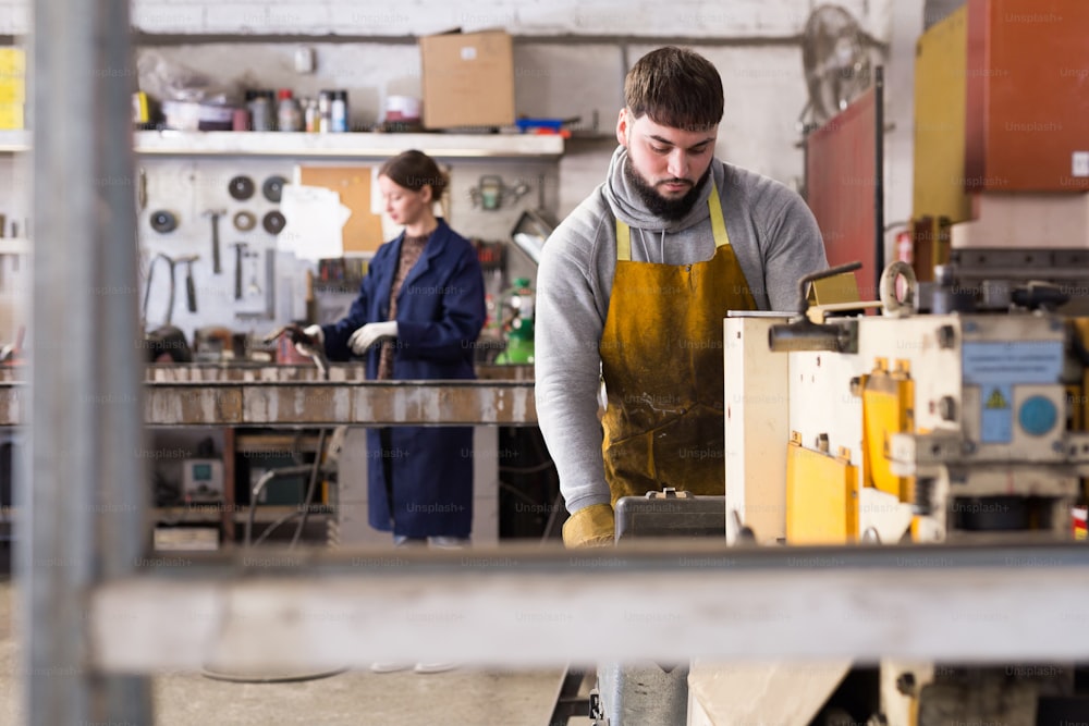 Portrait of man working with drilling machine on metal plate