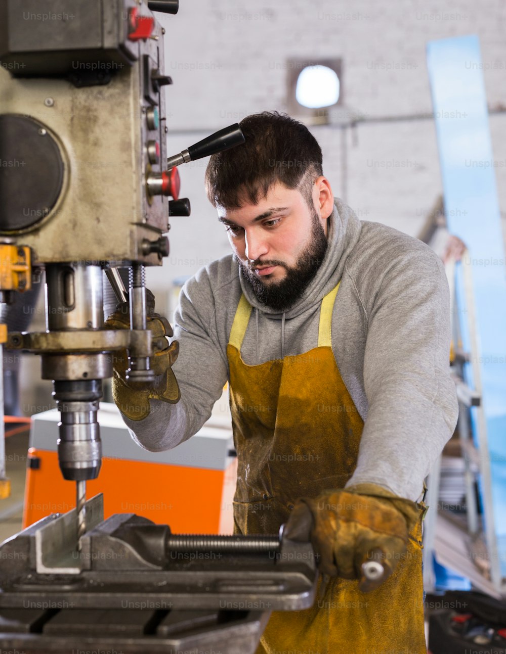 Retrato de un mecánico seguro de sí mismo usando una máquina perforadora en el taller