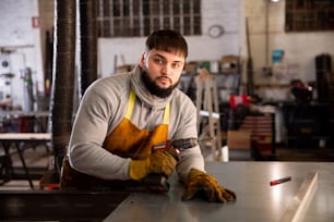 Portrait of confident  man  mechanic drilling metal sheet  in workshop