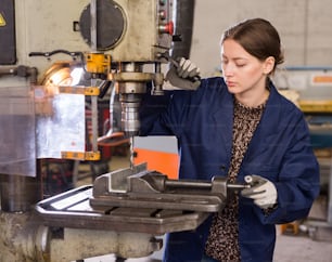 Porträt einer selbstbewussten Mechanikerin, die eine Bohrmaschine in der Werkstatt benutzt
