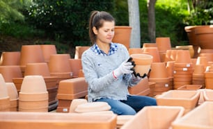 Woman chooses pots clay pots in store warehouse
